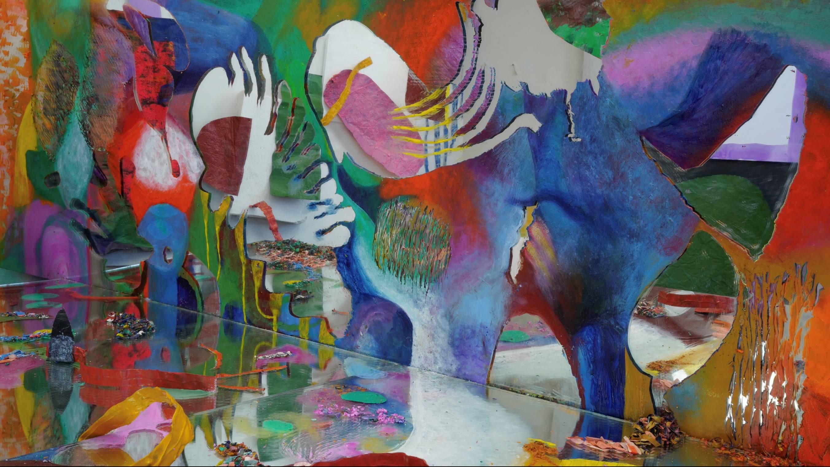 Abstract film still with a mirrored surface reflecting vibrant colors, layered shapes, and textured surfaces.