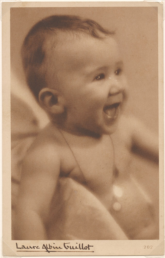 Sepia-toned photo of a laughing baby with visible tiny teeth.