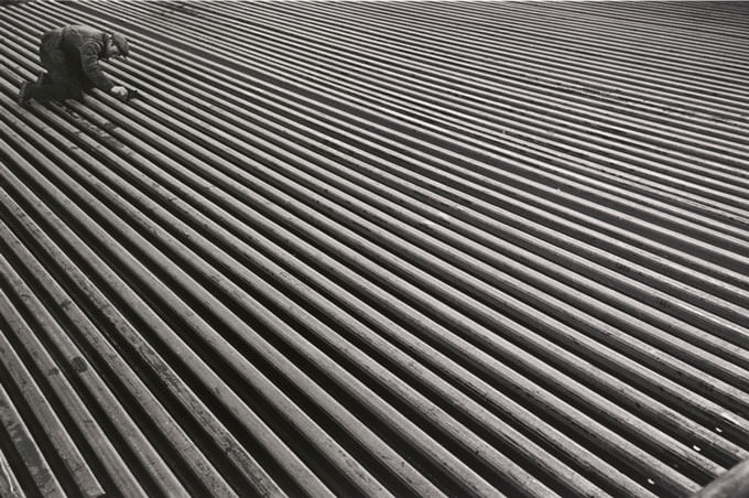 An inspector kneels on rows of rails in a factory.