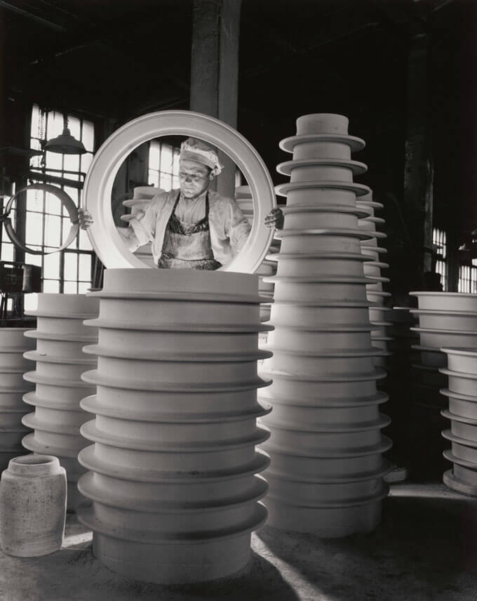 A black and white photo of a person inspecting insulators in an industrial setting.
