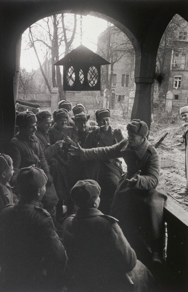 A black and white photo of a soldier telling a story to his fellow soldiers surrounding him.