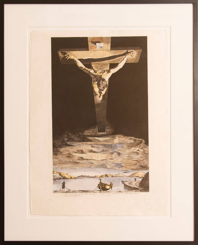 A person hangs on a cross suspended in a black sky above a landscape of sky and water containing a boat and three small figures