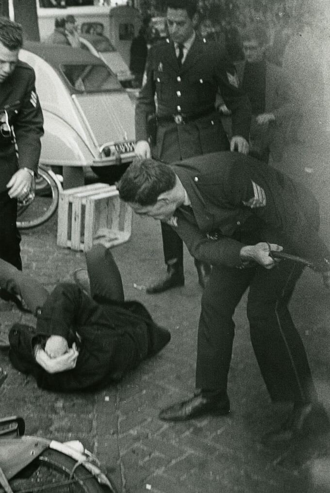 Policeman hits a protestor, while he cowers on the ground (Amsterdam, Holland)