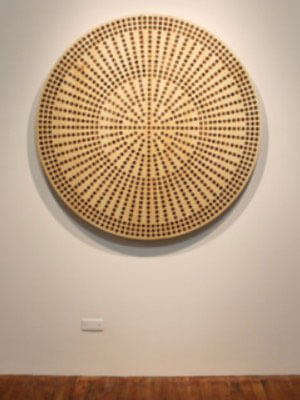 Flat wooden circle with a pattern of concentric circles made of evenly spaced pennies embedded in the wooden surface