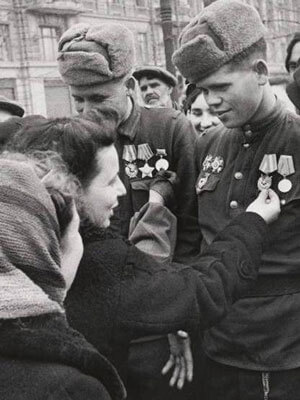 Soldiers with medals surrounded by a crowd in a city setting.