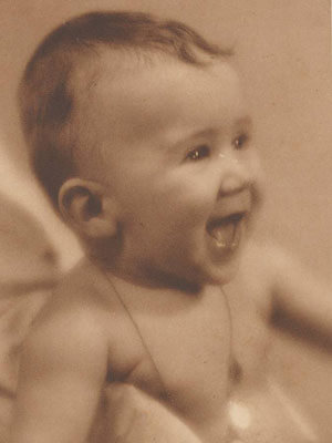 Sepia-toned photo of a laughing baby with visible tiny teeth.