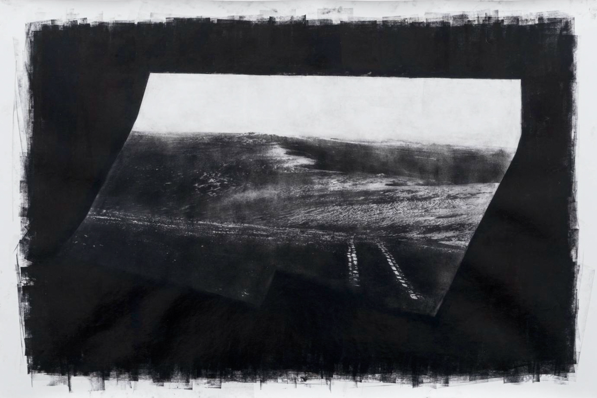 A black-and-white photograph of a landscape and train tracks on a dark background in a white frame.