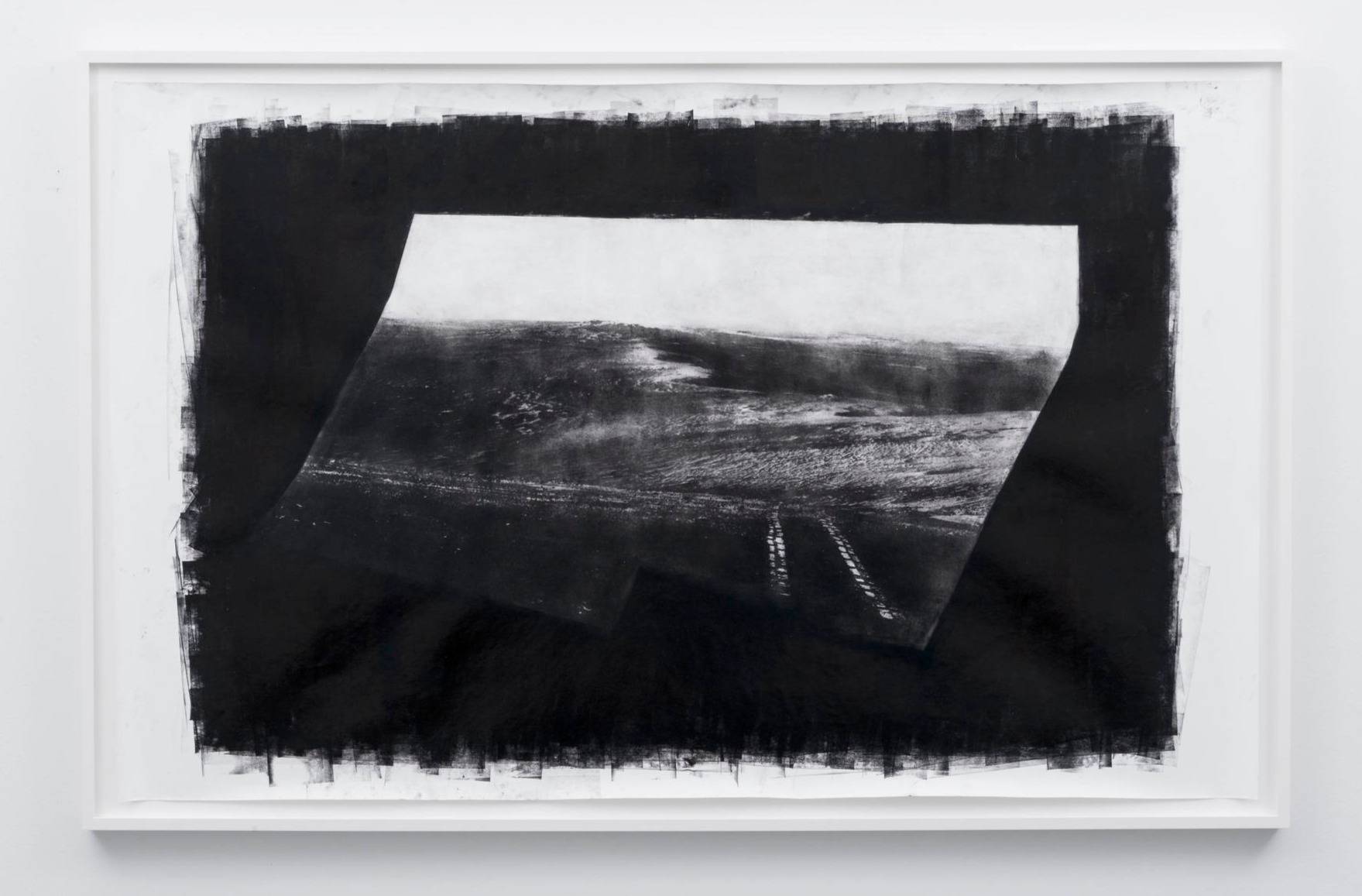 A black-and-white photograph of a landscape and train tracks on a dark background in a white frame.