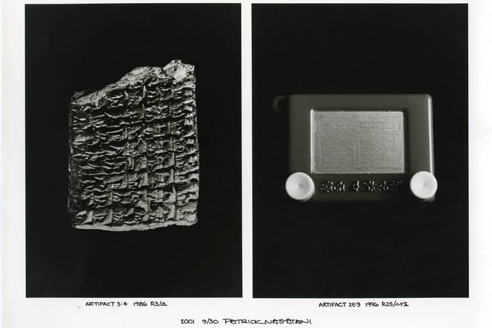 A clay tablet with cuneiform script and a toy Etch A Sketch displayed side by side.