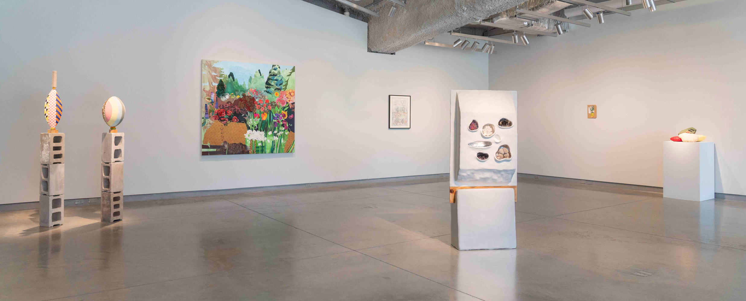 An art gallery with six works on display that are a mix of sculptures and works on hung on the wall.